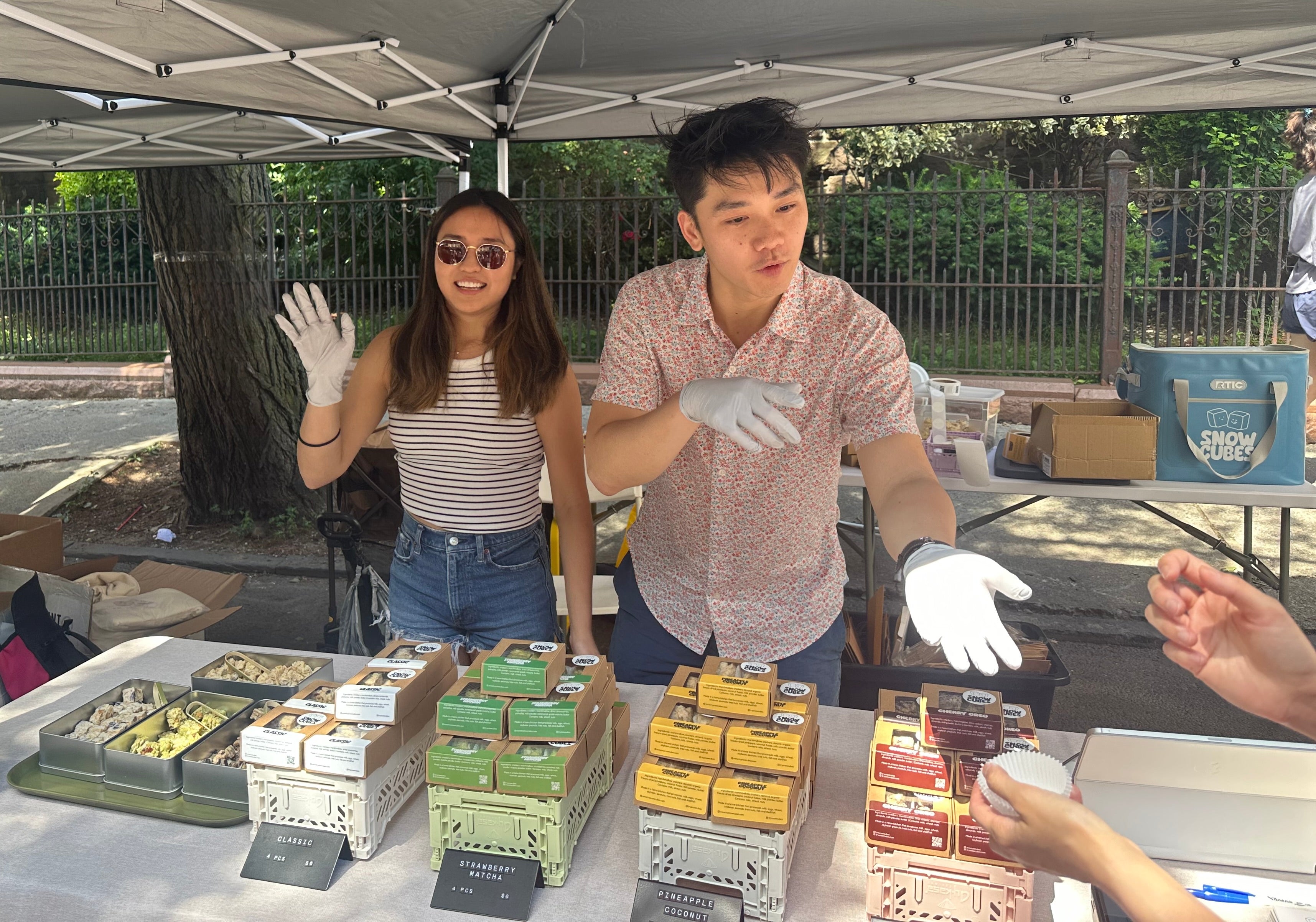 Two people running a Snowcubes booth at a fair