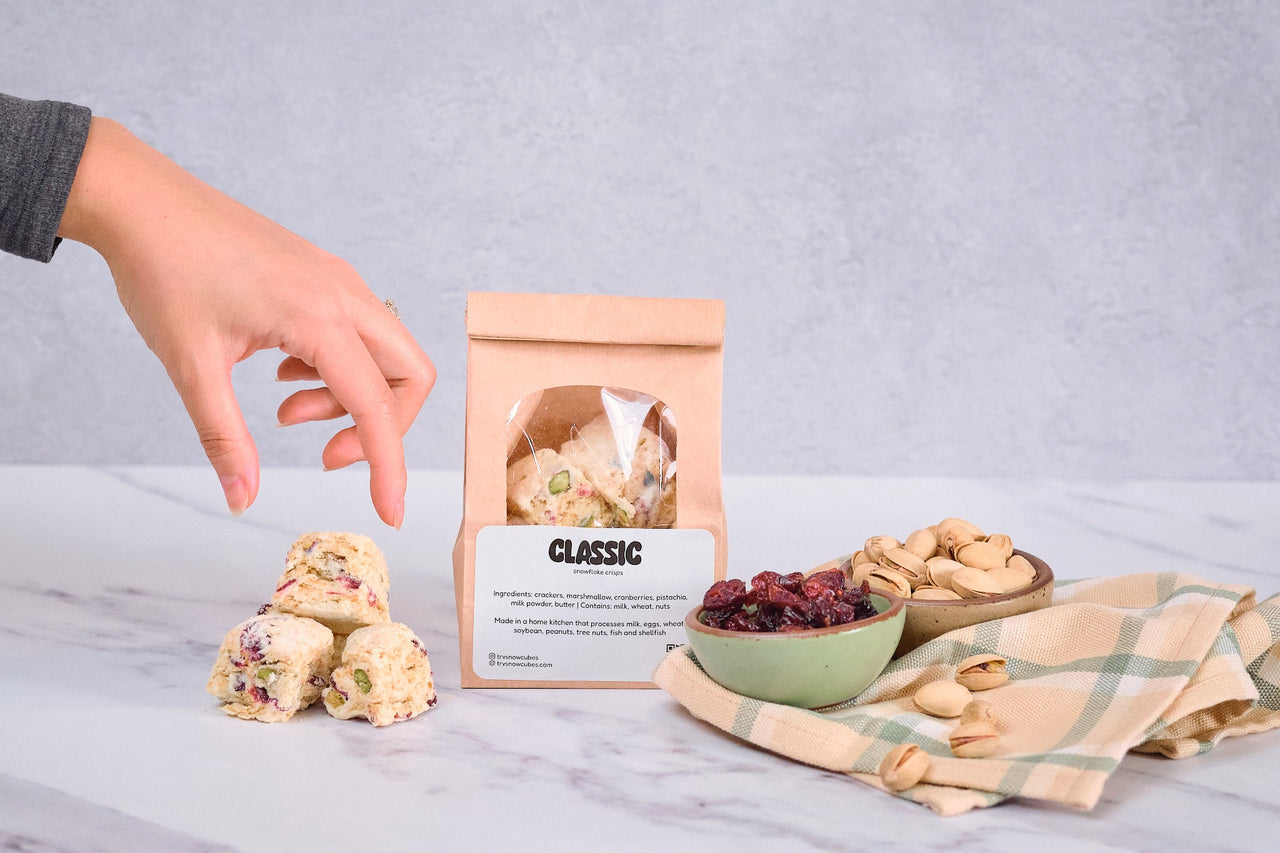 Cut classic snowflake crisps beside bowls of dried cranberries and pistachios, next to a Classic pouch