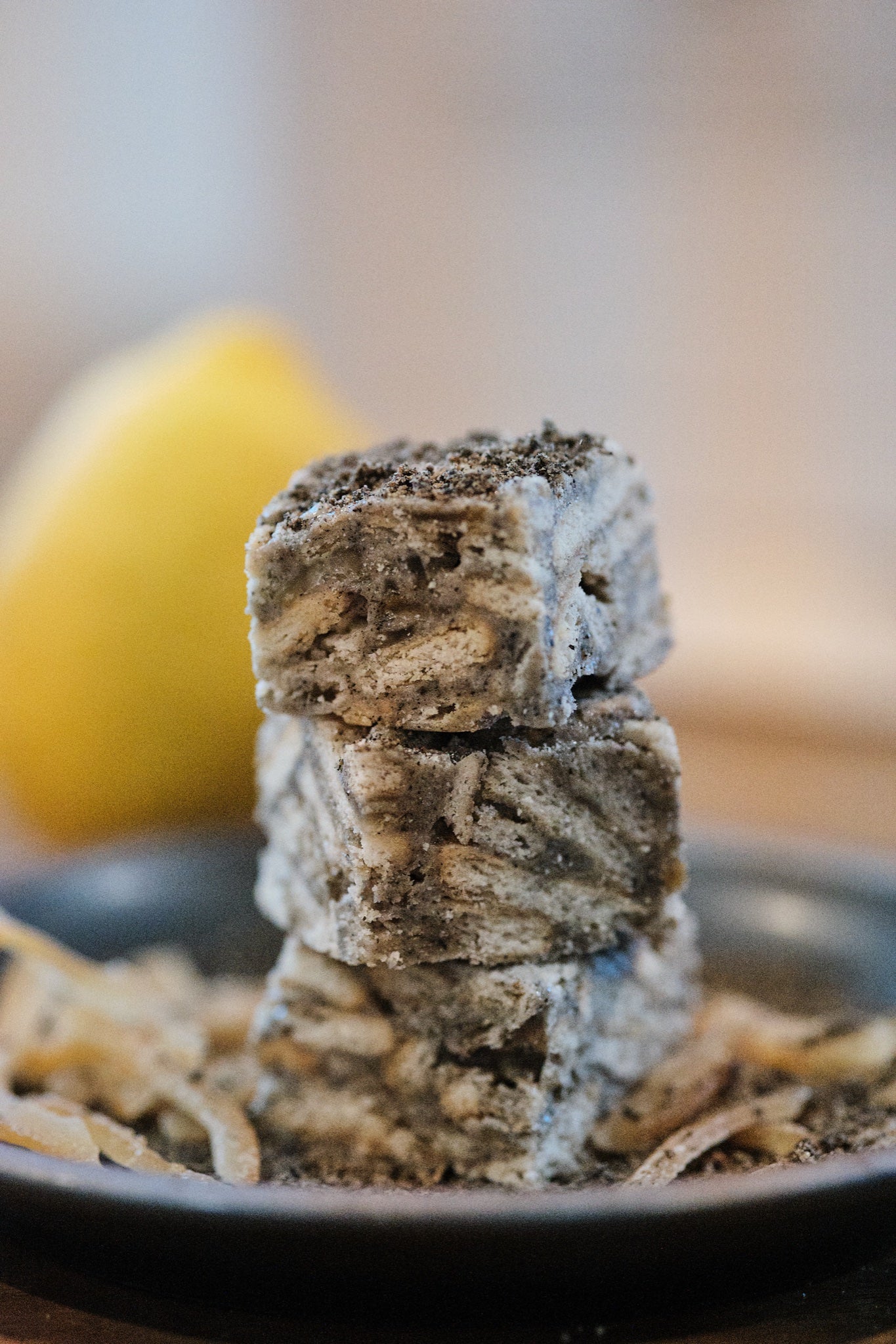 Black Sesame Yuzu Snowcubes — stack of three crisps dusted with black sesame, candied yuzu peel and fresh lemon behind