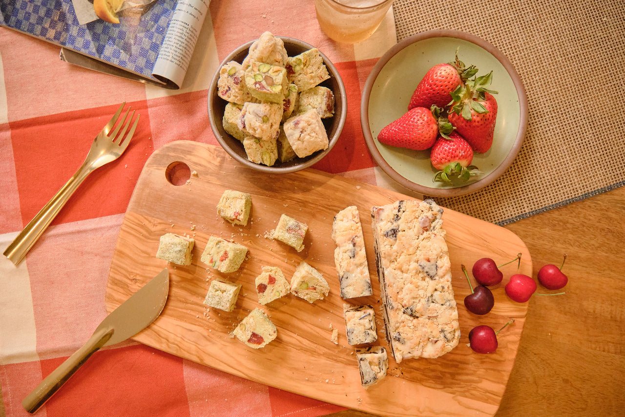 A sliced Snowcubes snowflake crisp slab on a wooden board with fresh strawberries and cherries