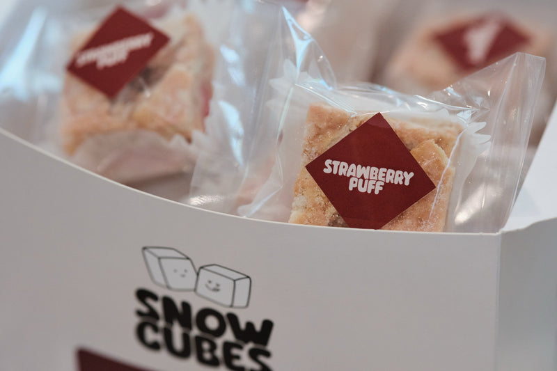Individually wrapped Strawberry Puff Snowcubes in an open Snowcubes box
